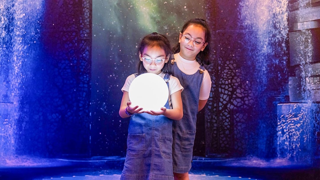 Children holding a glowing orb at La Perle by Dragone show.
