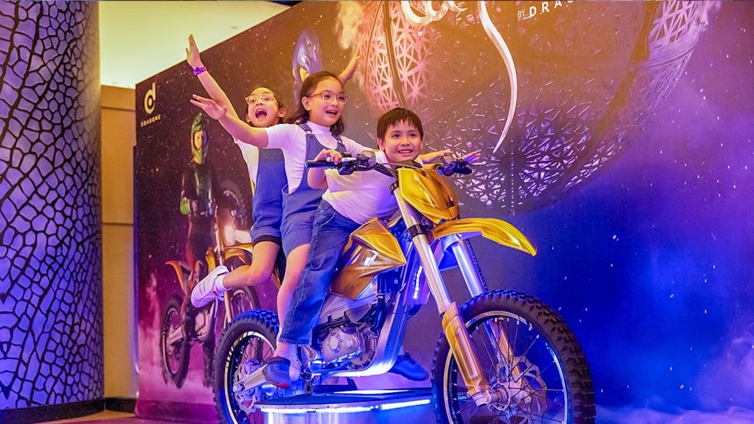 Children posing on a display motorcycle at La Perle by Dragone in Dubai.