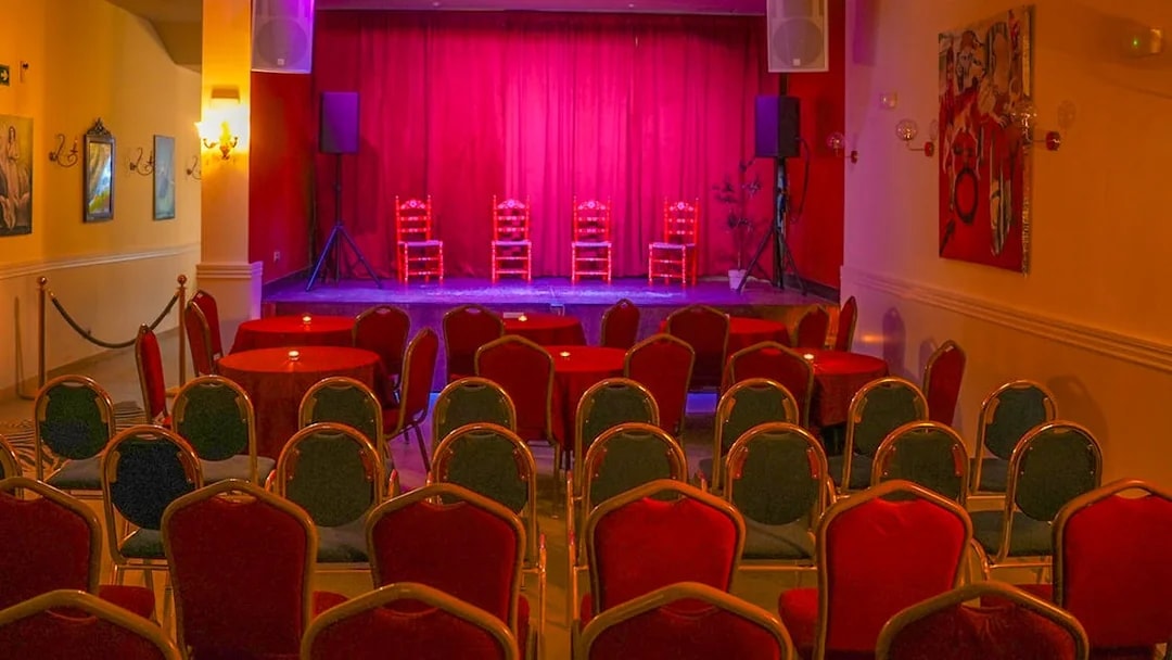 Flamenco Laietana stage with red chairs and tables in a dimly lit venue.
