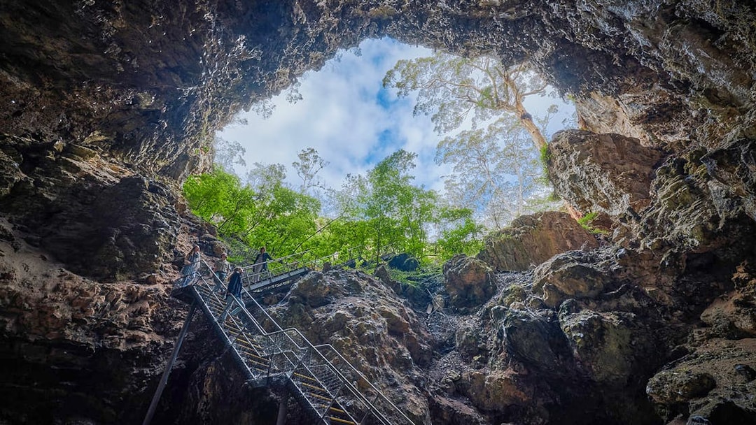 Stairs leading up from Lake Cave sinkhole entrance, Margaret River, with trees and sky above.