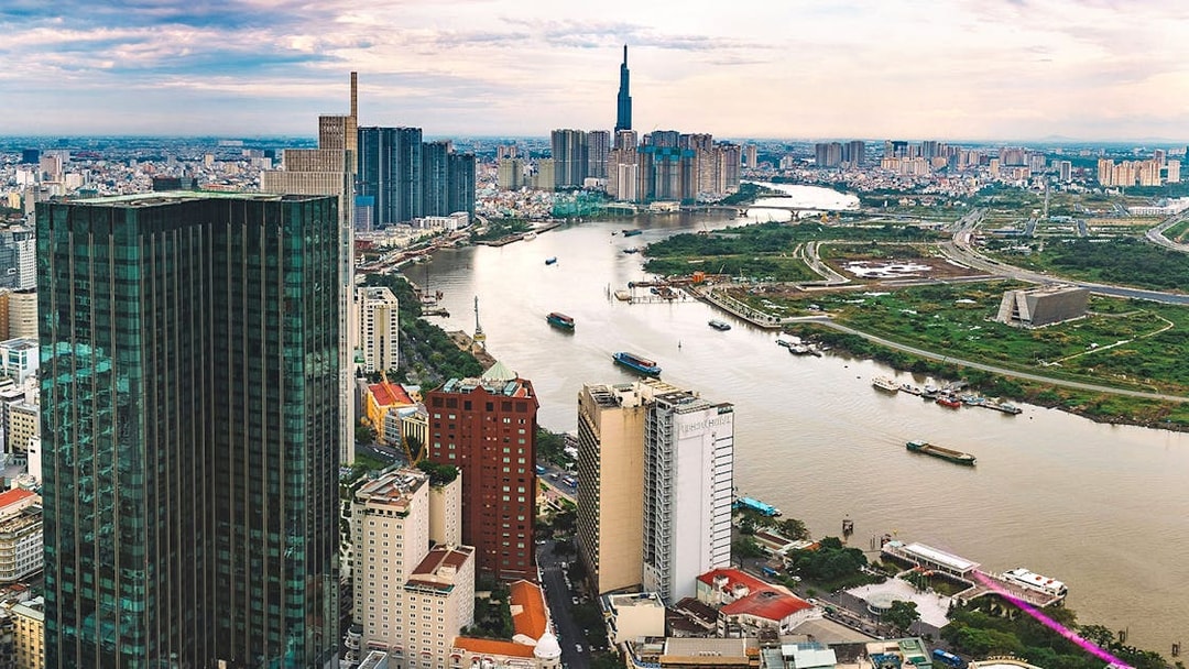 Panoramic view of downtown Ho Chi Minh City from a sky deck, featuring the Saigon River and skyscrapers.