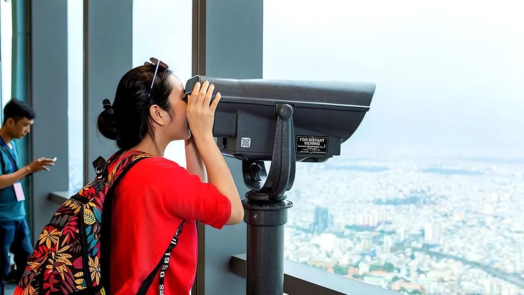 Visitor using telescope at Saigon Skydeck overlooking Ho Chi Minh City.
