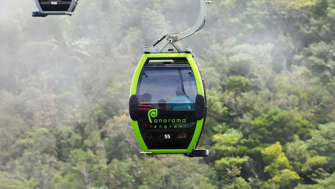 Langkawi Cable Car gondola ascending over lush green forest.