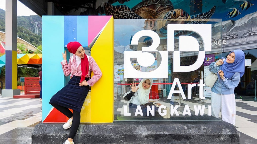 Women posing at 3D Art Langkawi entrance.
