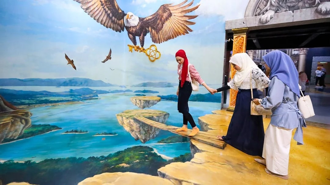 Visitors at 3D Art Langkawi interact with an optical illusion of an eagle and floating islands.