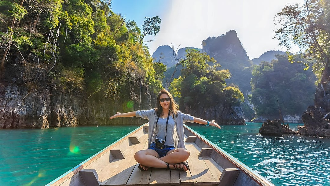 Woman sitting on a long-tail boat in the Andaman Sea with limestone cliffs in the background.