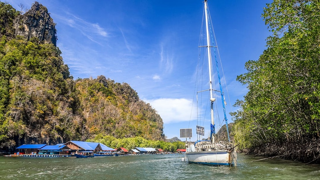 Sailboat near floating fish farm and mangroves on Andaman Sea, Langkawi Island tour.