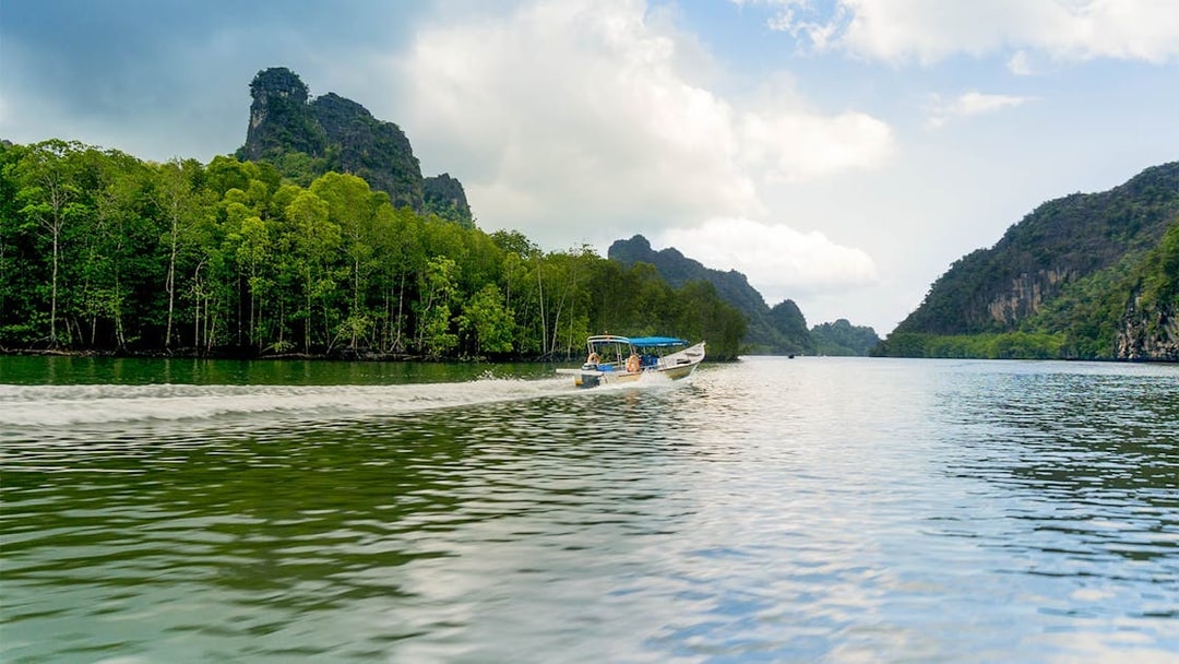 Speedboat cruising along the riverside of Kilim Park with lush greenery and rocky hills.
