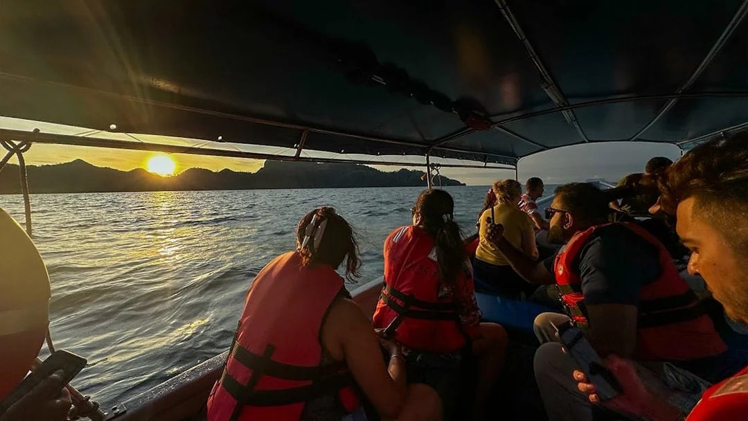 Passengers on boat watching sunset over water during Langkawi mangrove tour.