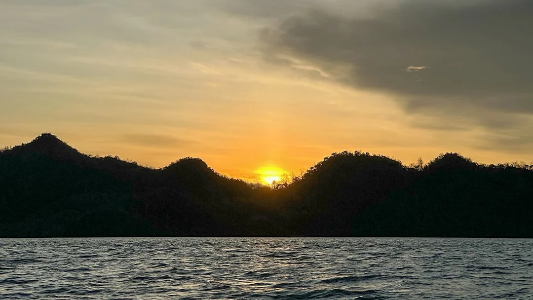 Sunset over water with silhouetted islands during Langkawi mangrove tour.