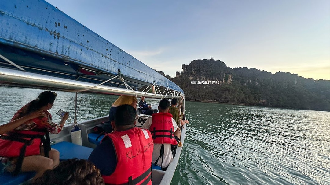Tourists on a boat view Kilim Geoforest Park sign from the water in Langkawi.