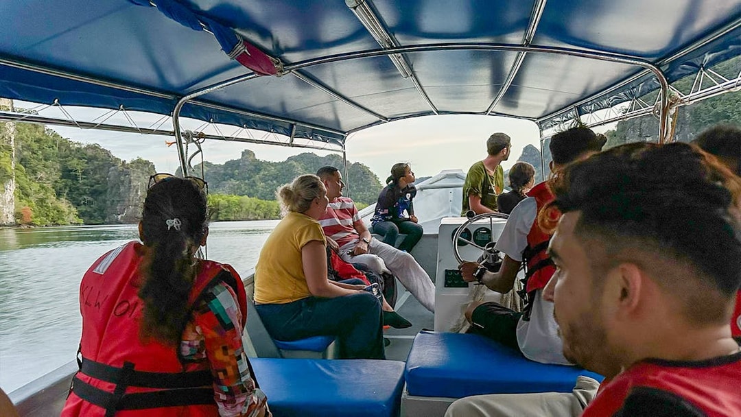 Passengers on a covered tour boat viewing karst landscape during Langkawi mangrove tour.