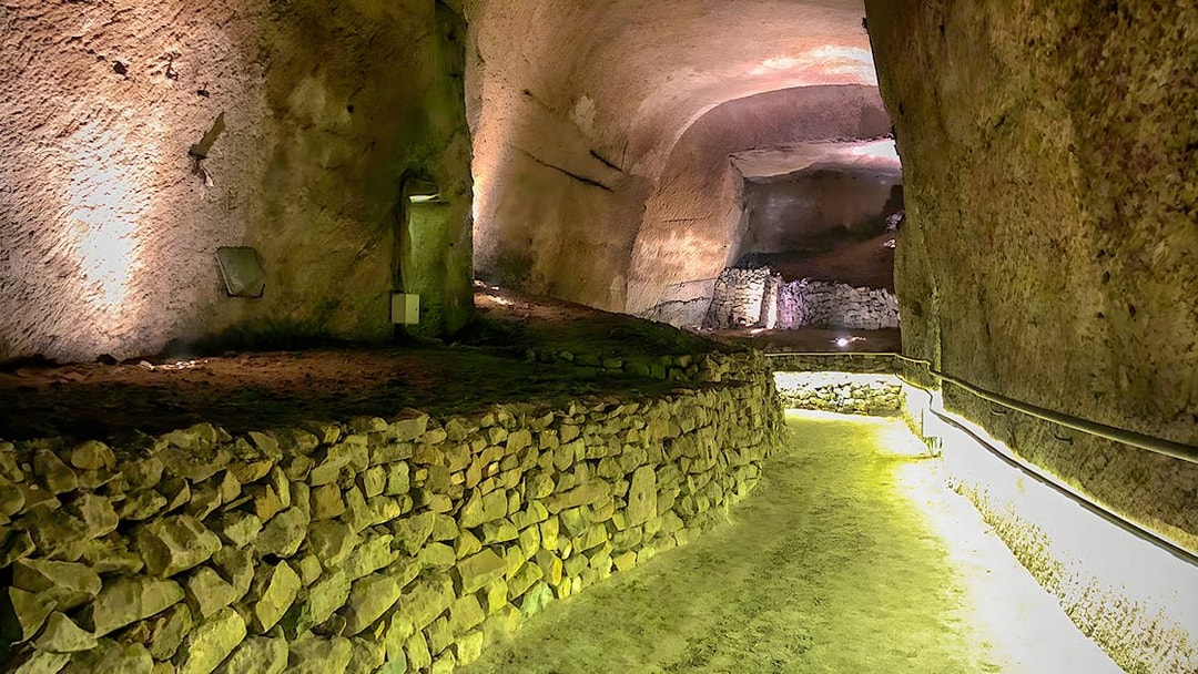 Naples' LAPIS Museum underground passage with ancient stone walls, part of a guided tour.