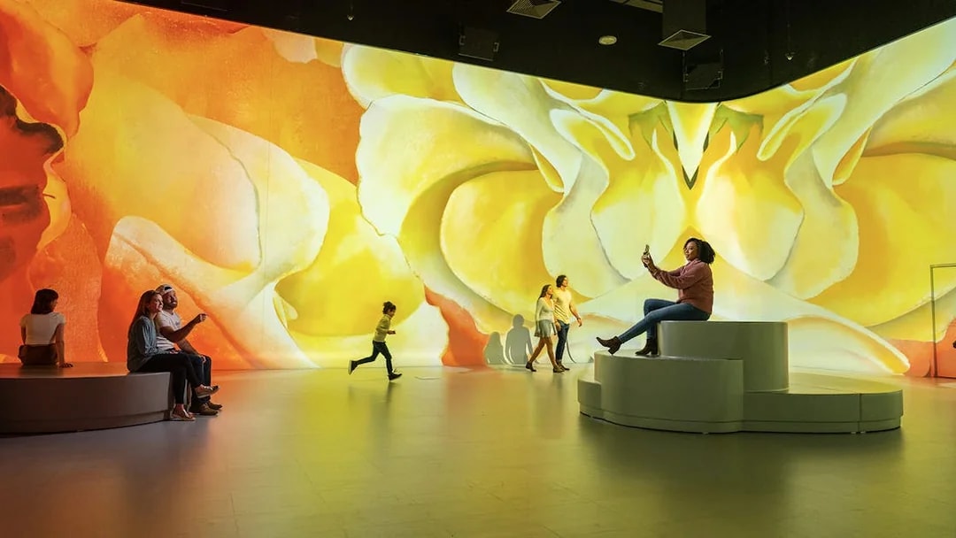 Visitors enjoying immersive art exhibit in Las Vegas with vibrant floral projections.