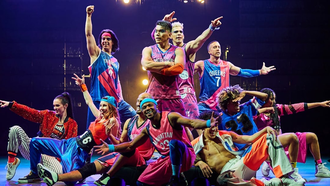 Performers in vibrant costumes on stage during a Las Vegas show, part of Go City pass attractions.