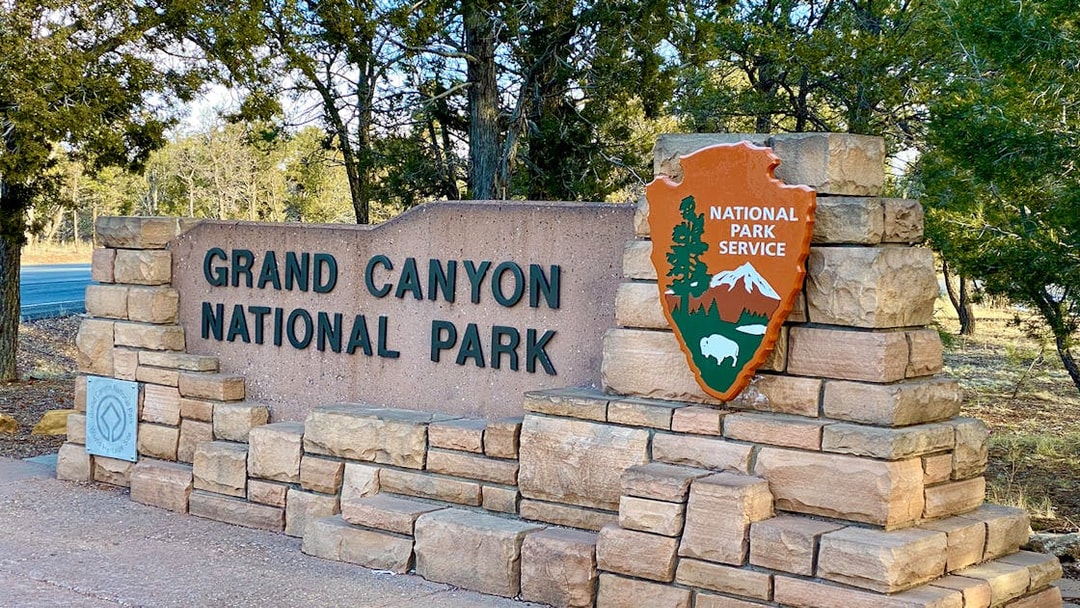 Grand Canyon National Park entrance sign with National Park Service emblem.