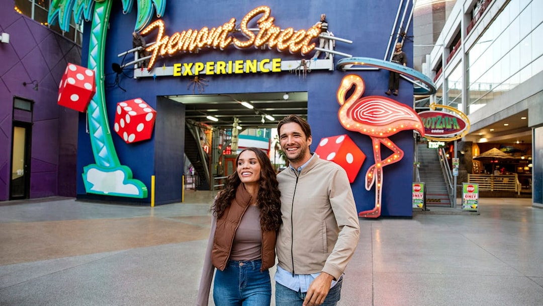 Couple walking at Fremont Street Experience, Las Vegas, with neon signs and dice.