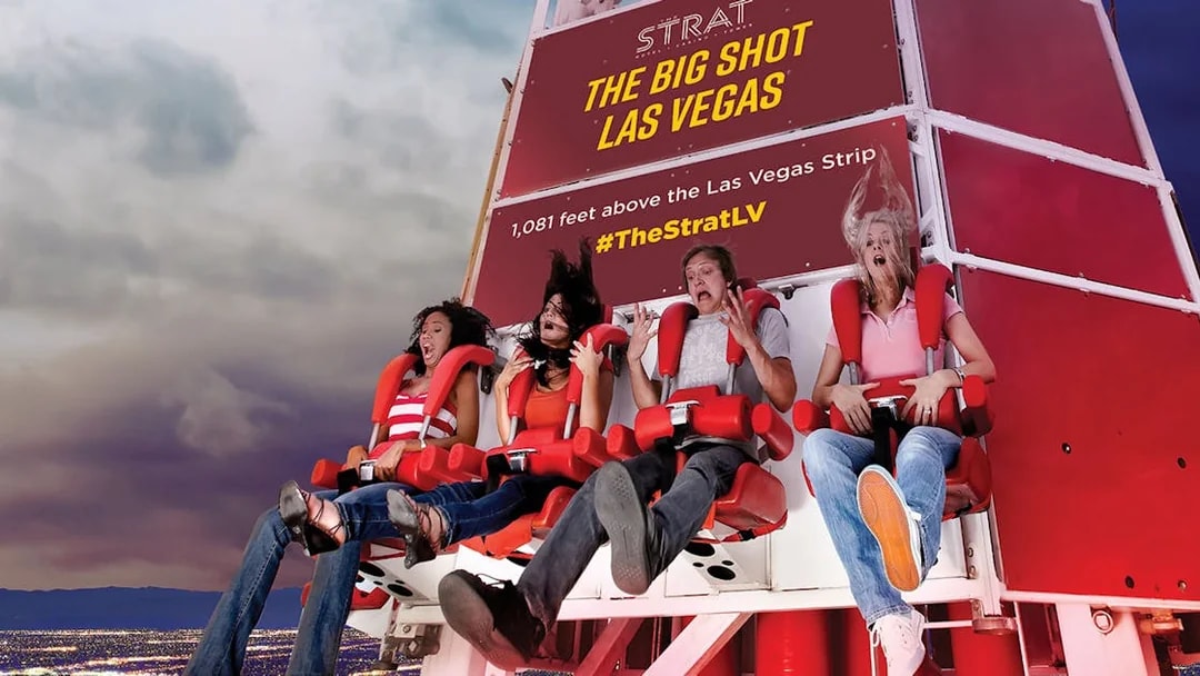 Riders on the Big Shot thrill ride at The Strat, Las Vegas, with city lights below.