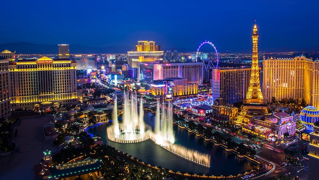 Las Vegas Strip at night with Bellagio fountains and Eiffel Tower replica.