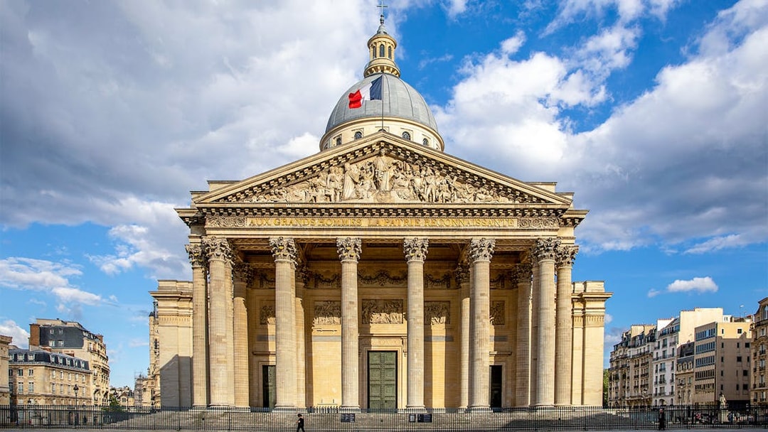 Pantheon in Paris with neoclassical facade and French flag on dome.