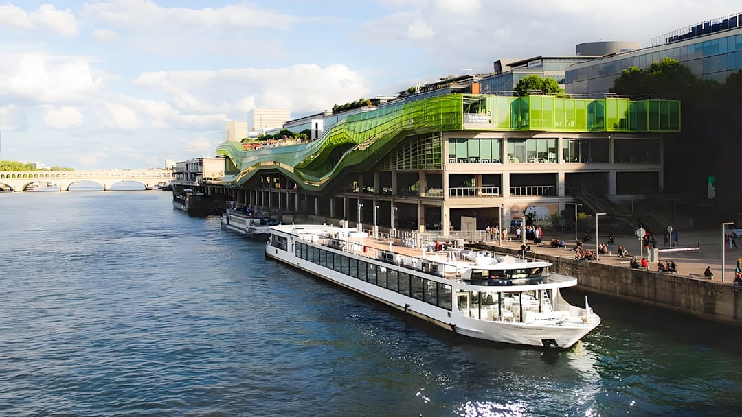 Seine River cruise boat docked near modern green building in Paris.