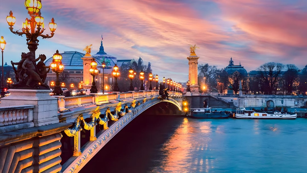 Pont Alexandre III at sunset with boats on the Seine River, Paris.