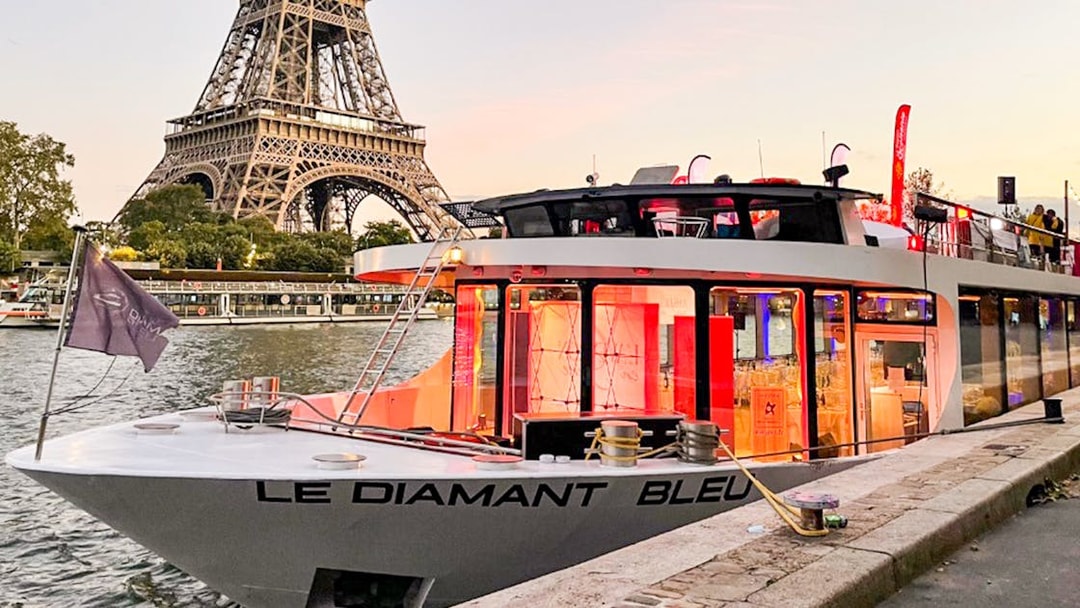 Le Diamant Bleu cruise boat docked on Seine River with Eiffel Tower in background.