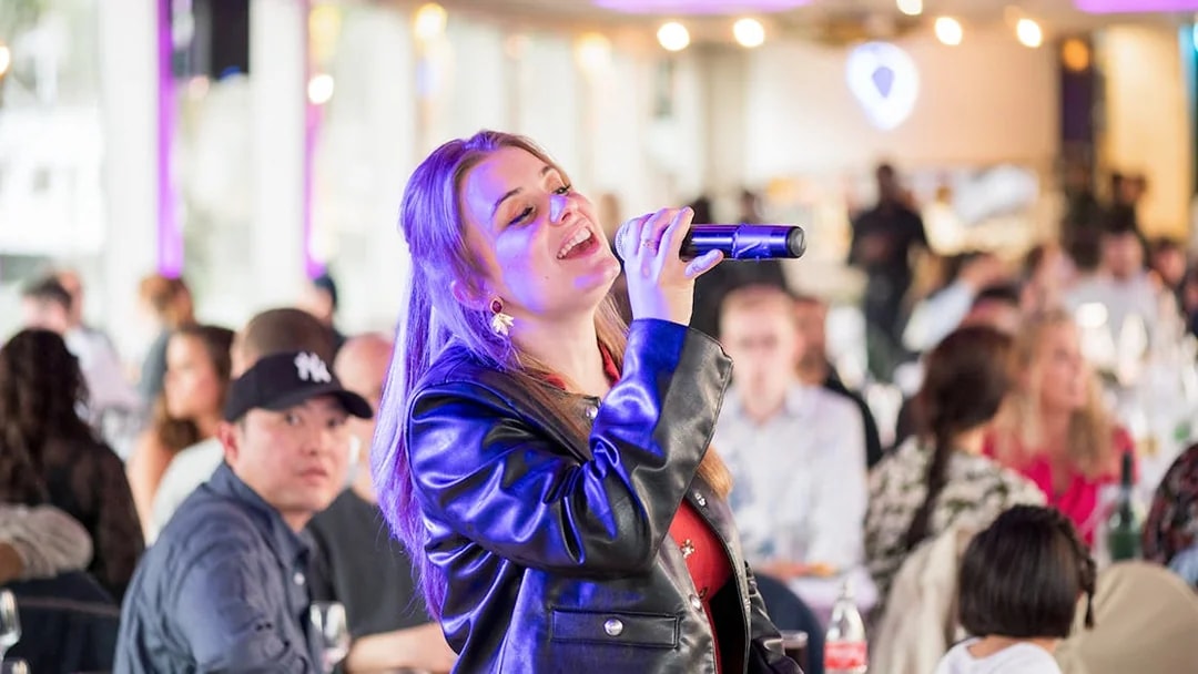 Singer performing on Le Diamant Bleu cruise with audience in background.