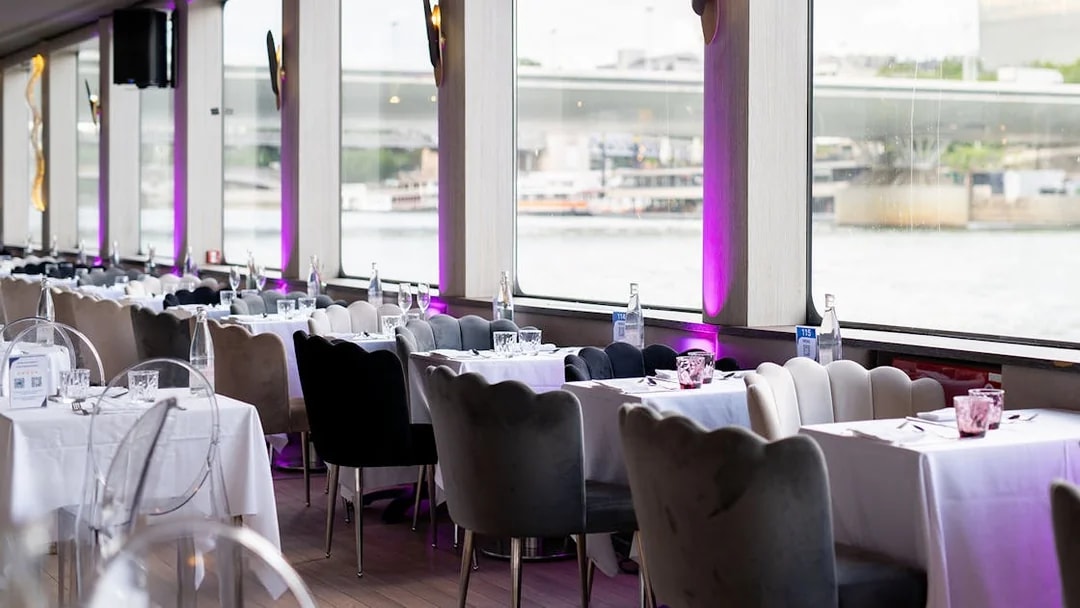 Dining tables set for Le Diamant Bleu Seine River Dinner Cruise in Paris.
