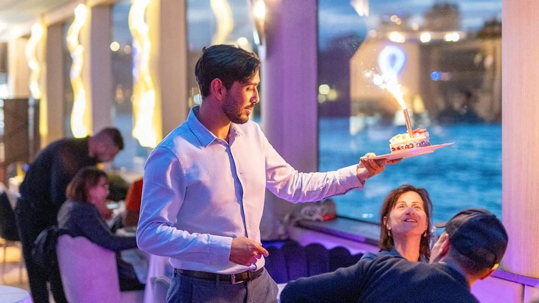 Server presenting dessert with sparkler on Seine River cruise in Paris.