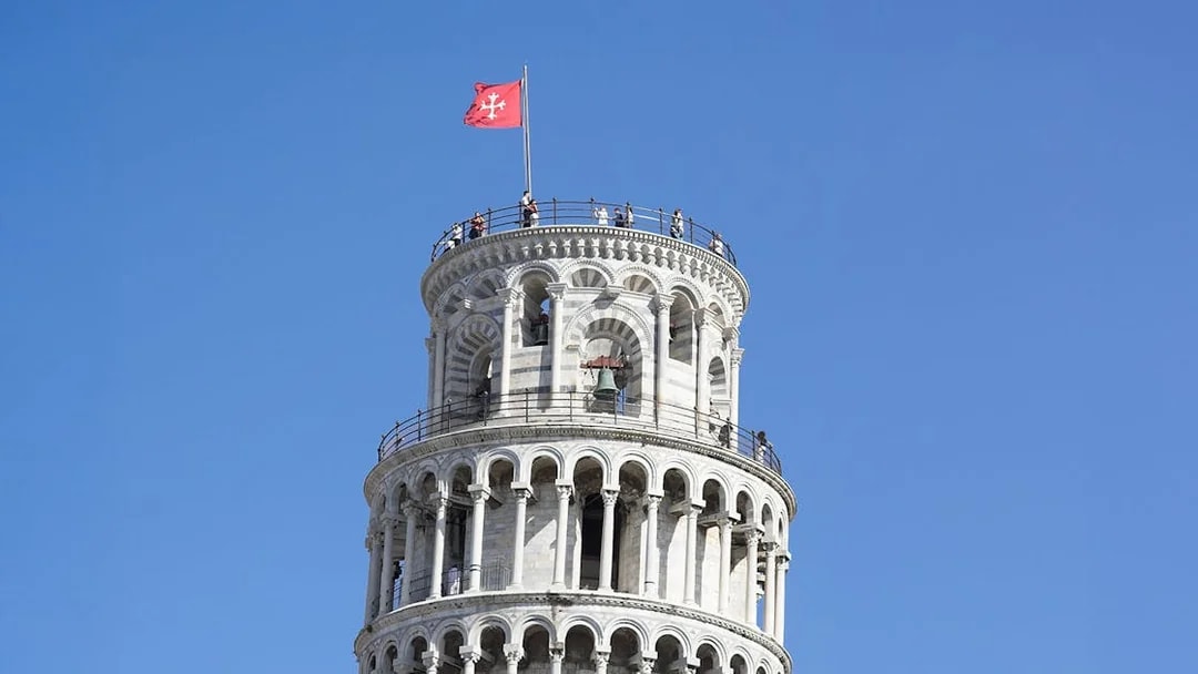 Tourists atop Leaning Tower of Pisa enjoying panoramic views.