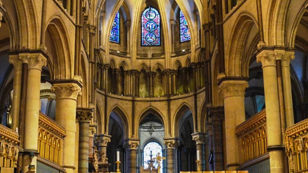 Interior of Canterbury Cathedral with stained glass windows and Gothic arches.