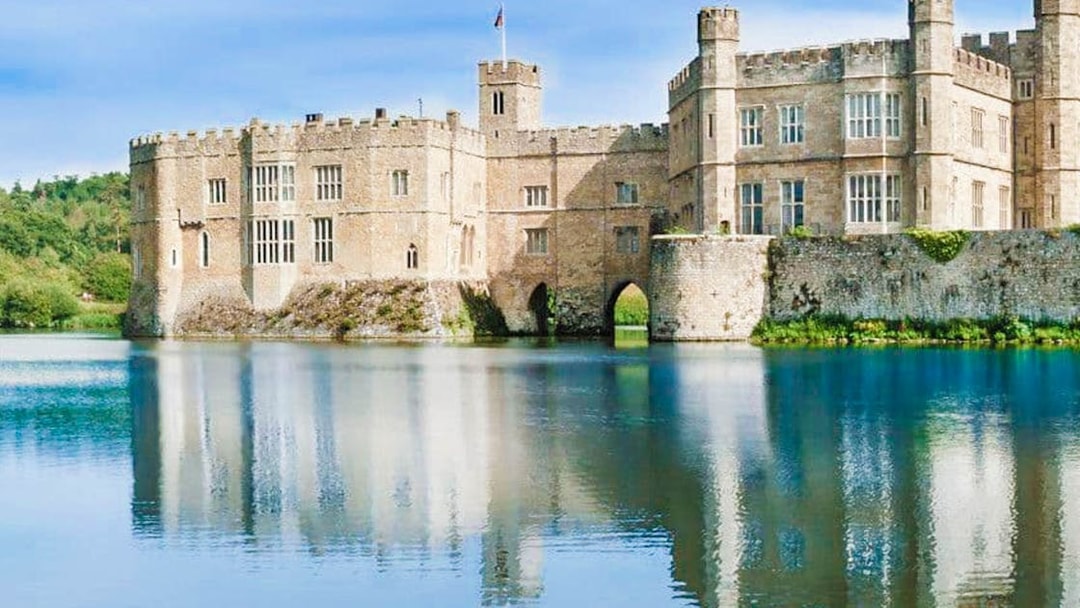 Leeds Castle reflected in a serene lake, part of the Leeds Castle, Canterbury Cathedral & White Cliffs of Dover Tour.