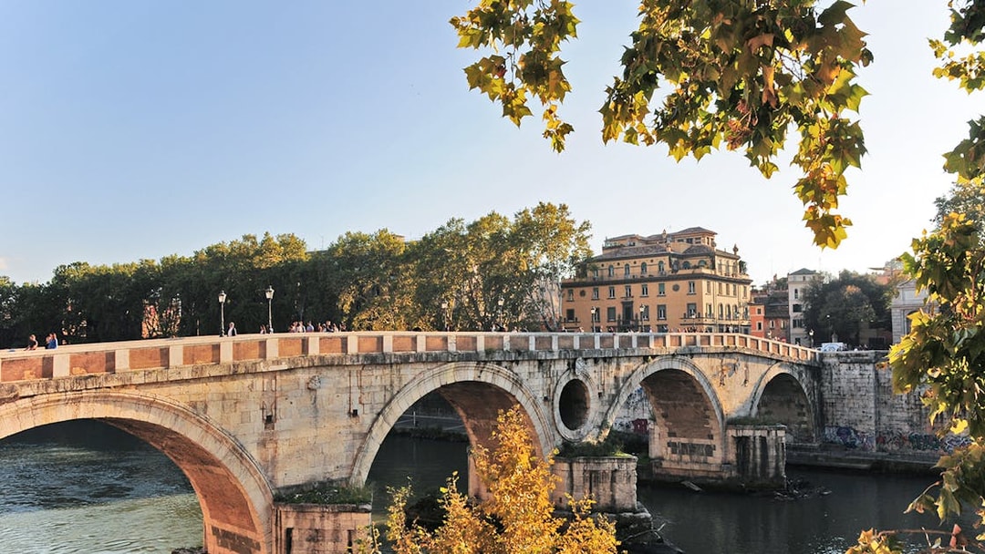 Ponte Sisto bridge over the Tiber River in Rome with trees and buildings in the background.