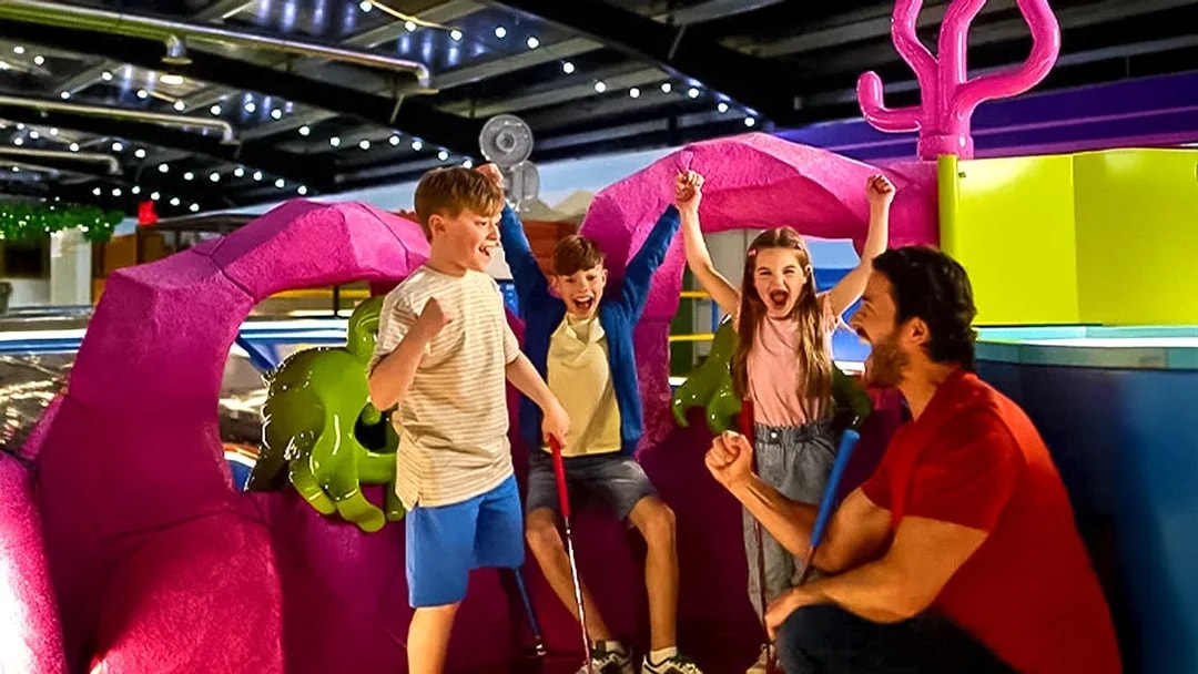 Children and adult celebrating at LEGOLAND® Adventure Golf indoor course.