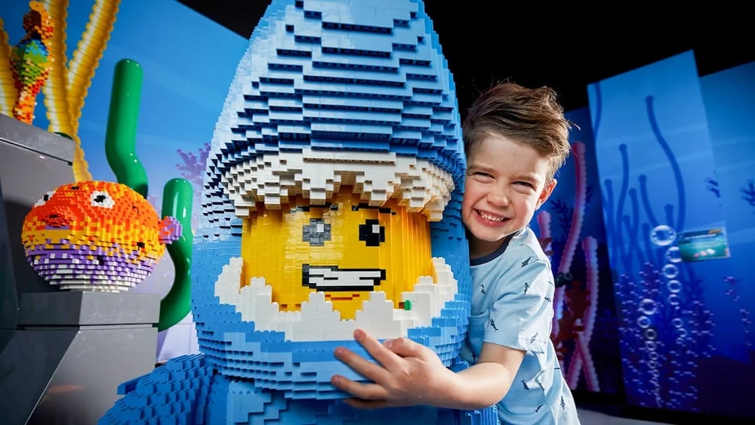 Child hugging LEGO shark figure at LEGOLAND Discovery Centre.
