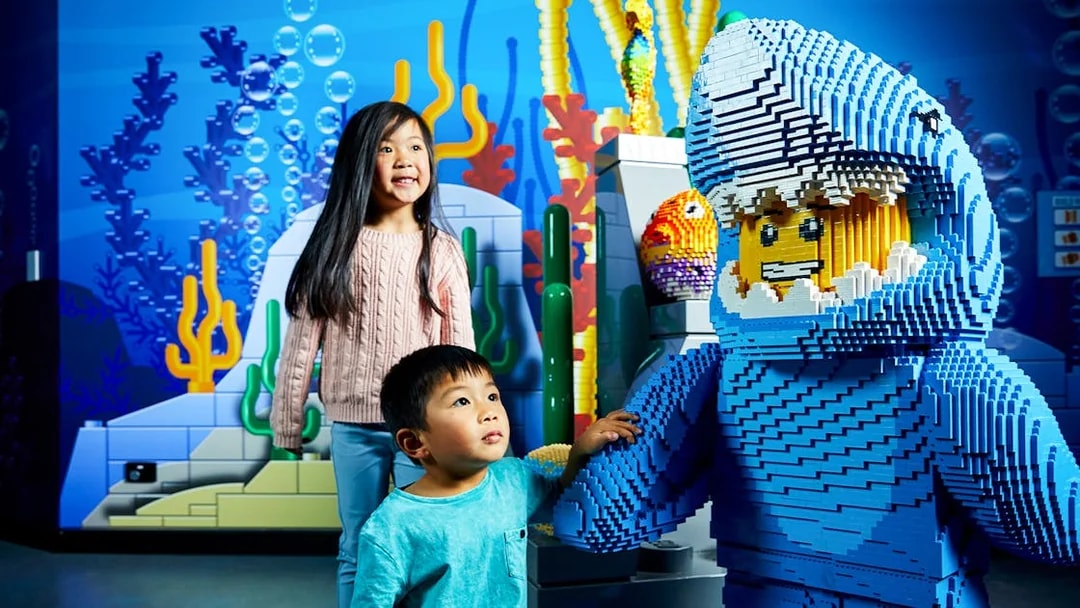 Children interacting with a LEGO shark figure at LEGOLAND Discovery Centre.