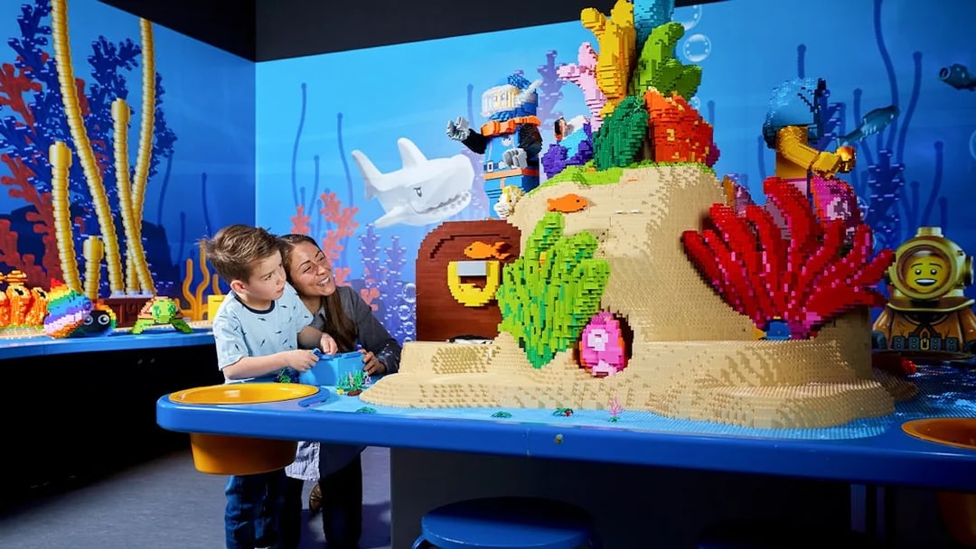 Child and adult exploring LEGO underwater scene at LEGOLAND Discovery Centre.