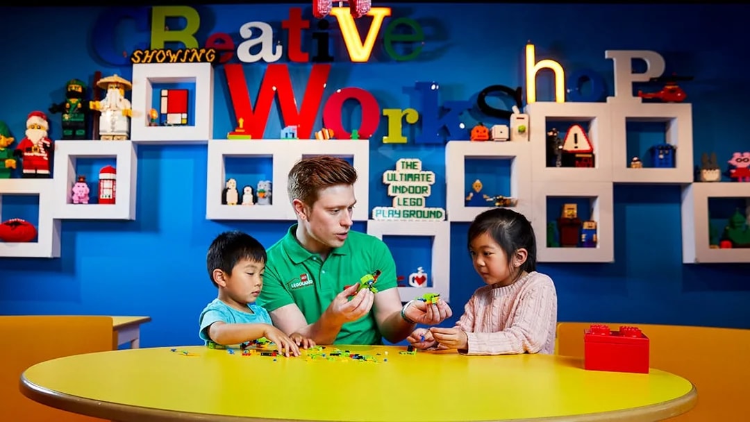 Children building LEGO models with instructor at LEGOLAND Discovery Centre.