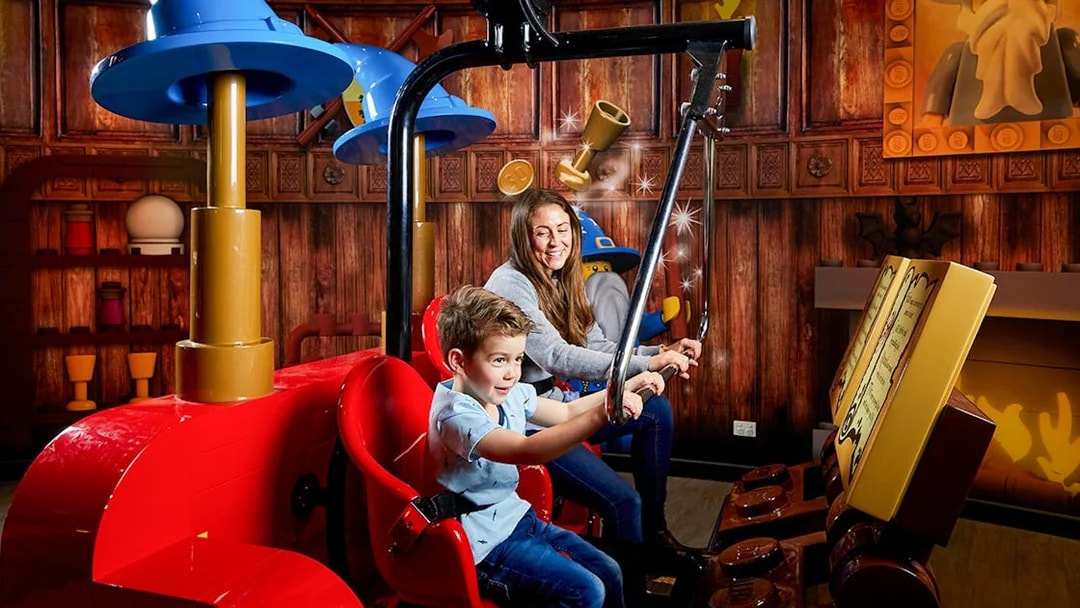 Child and adult enjoying interactive ride at LEGOLAND Discovery Centre.
