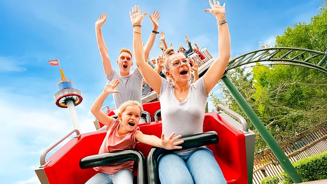 Guests on a roller coaster at LEGOLAND® Deutschland with arms raised in excitement.