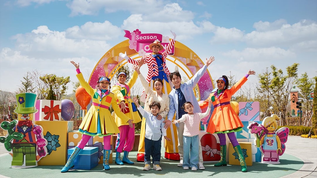 Family enjoying Legoland Korea with colorful performers and LEGO decorations.