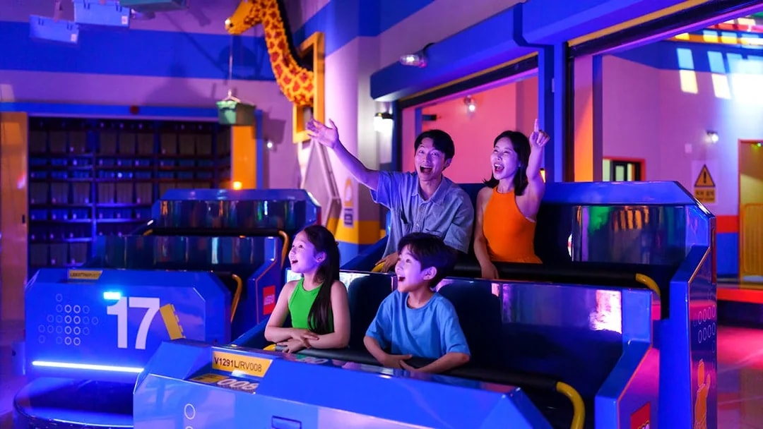 Family enjoying a ride at Legoland Korea with colorful lights and LEGO decorations.