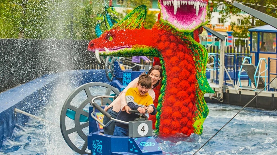Child steering a boat near a LEGO dragon at LEGOLAND Windsor Resort.
