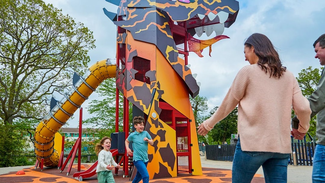 Children playing near dragon-themed slide at LEGOLAND® Windsor Resort.
