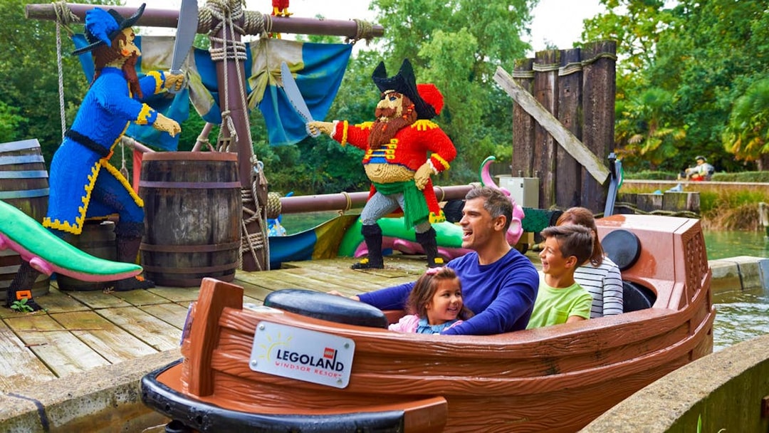 Family enjoying a boat ride past LEGO pirate figures at LEGOLAND Windsor Resort.