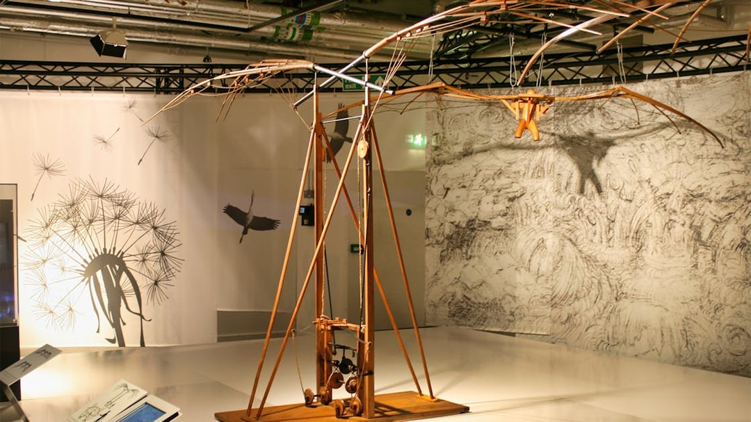 Leonardo Da Vinci Museum exhibit featuring a flying machine model with detailed sketches in the background.