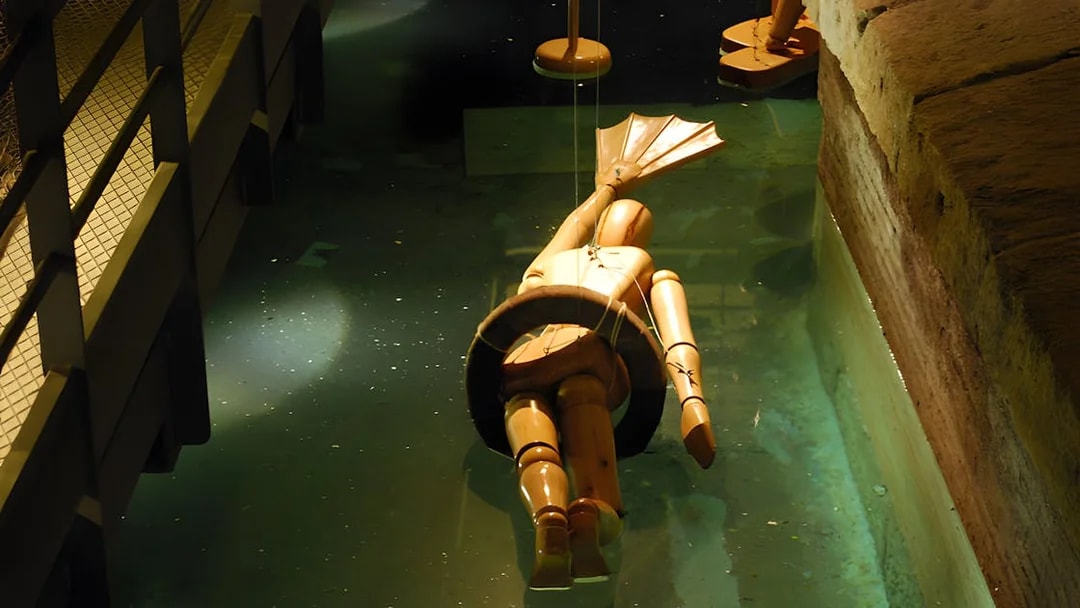 Wooden diving suit model in water at Leonardo da Vinci Museum exhibit.