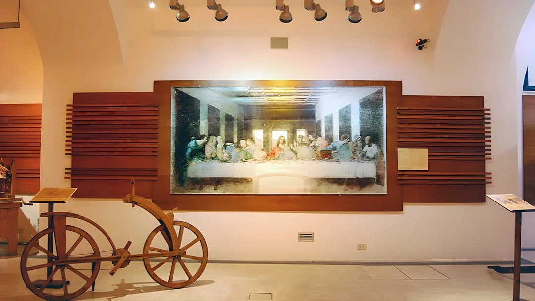 Exhibit of Leonardo da Vinci's Last Supper and wooden bicycle at museum.