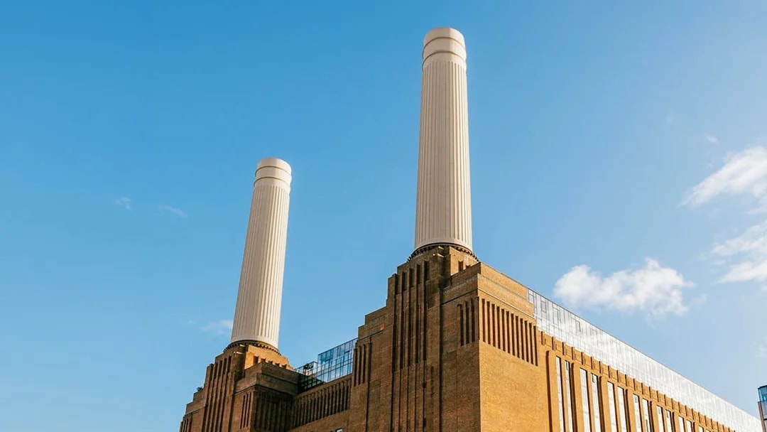 Battersea Power Station chimneys against a clear blue sky in London.